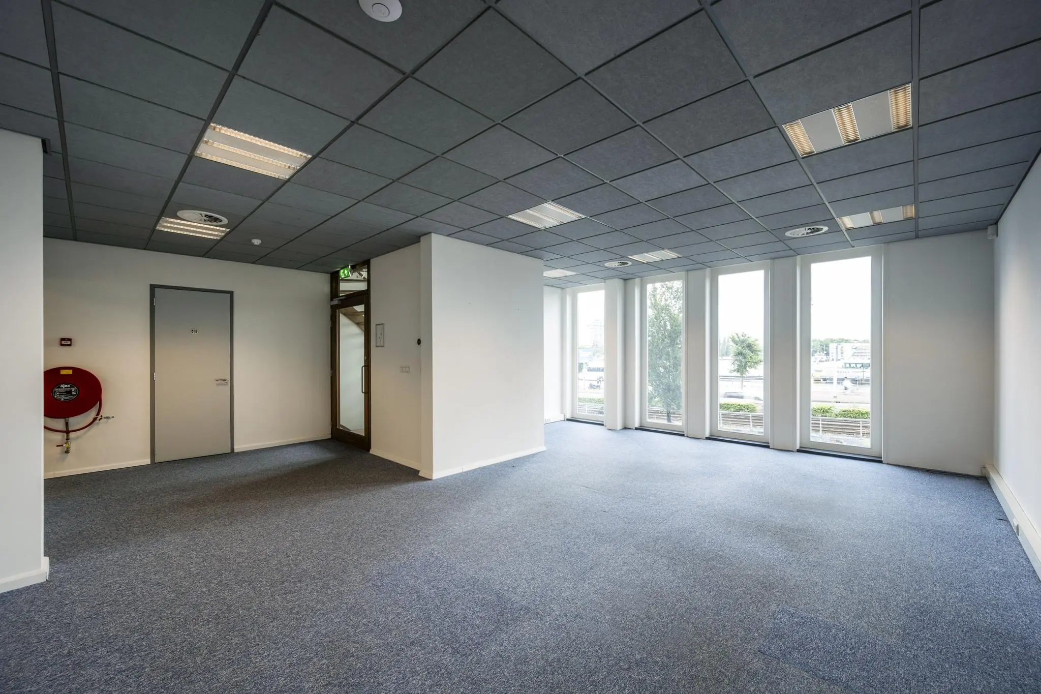 Lichte, lege kantoorruimte aan de De Ruijterkade met grote ramen en uitzicht op het water.